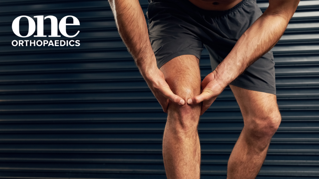 Person in running gear holding the back of the leg in what looks like pain potentially due to an ACL tear