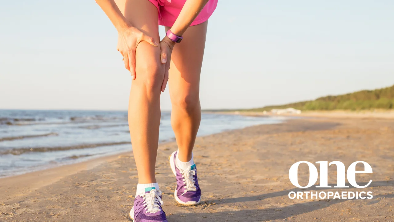 A person in running gear holding their right leg at the knee region, potentially feeling an ACL tear
