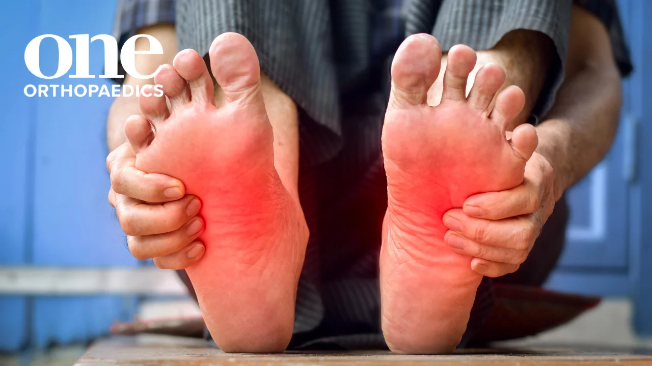 Someone holding their two feet in pain, with the feet highlighted in red potentially meaning it was sudden foot pain
