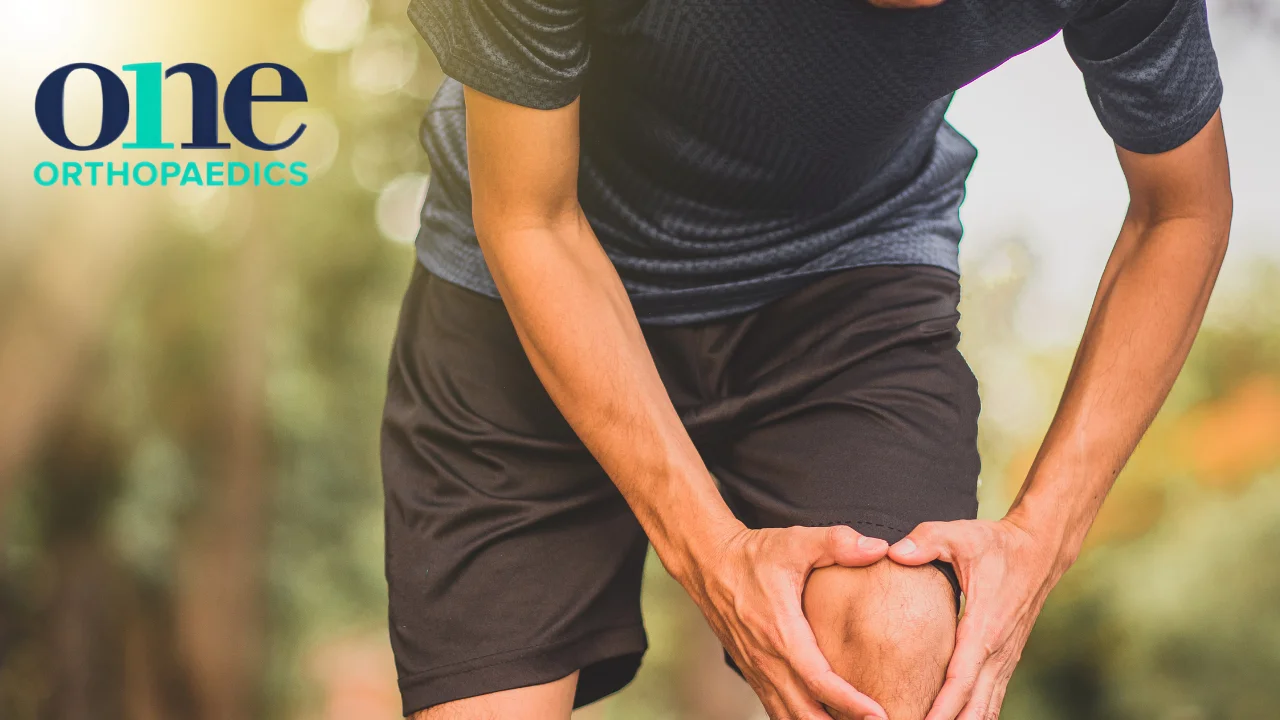 Person slightly bent over holding their knee in pain due to what might be a knee ligament injury